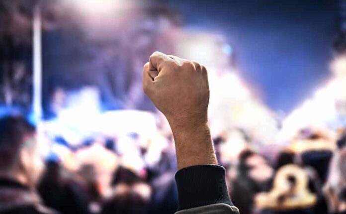 1227767950 featured image Raised fist in a crowd at night.