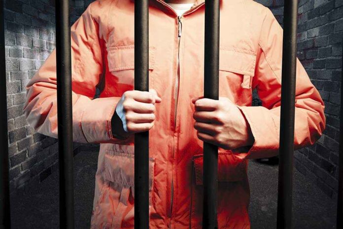 62493325 featured image Person in orange jacket behind prison bars