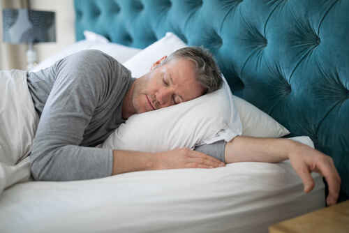shutterstock_697889302.jpg featured image Man sleeping on bed with teal headboard.
