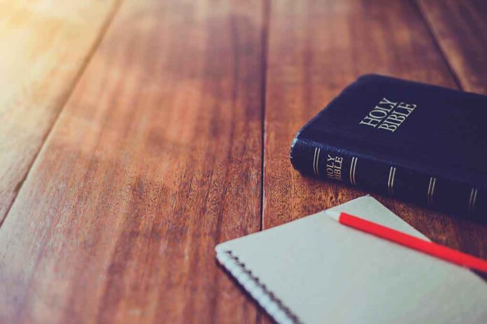 Bible and notebook on wooden table sunlight