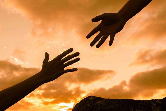 582394849 featured image Two hands reaching against a sunset background.