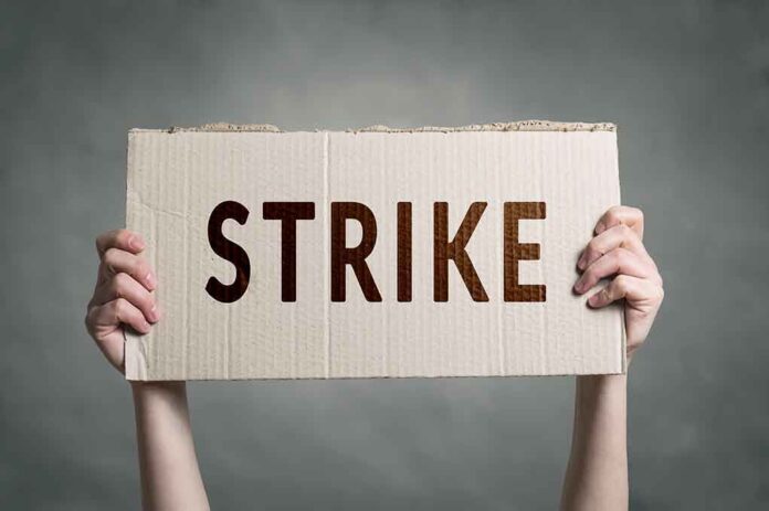 683350906 featured image Two hands holding a cardboard sign saying STRIKE