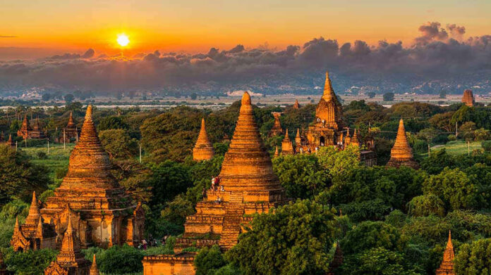 Sunset over ancient temple complex with lush greenery