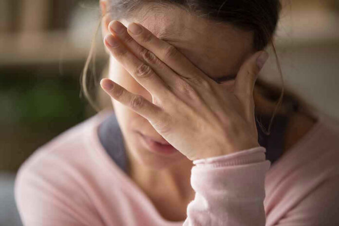 Woman covering face with hand looking stressed