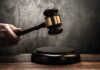 Hand holding judges gavel above wooden sound block