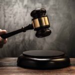 Hand holding judges gavel above wooden sound block