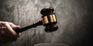 Hand holding judges gavel above wooden sound block