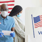 People voting with masks and gloves at polling station.