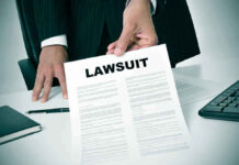 Person holding a document titled "LAWSUIT" in office.