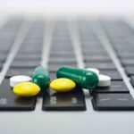 Various colored pills scattered on a laptop keyboard