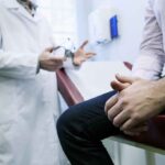 A doctor in a white coat discussing with a patient sitting on an examination table