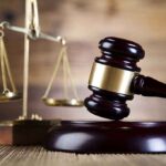 DA Faces Recall After Offender Walks Free A wooden gavel and scales of justice on a wooden surface