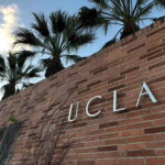 Brick wall with UCLA lettering and palm trees.