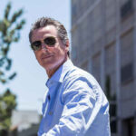 Newsom’s Silence on LA Shootings Condones Violence Man in sunglasses wearing a blue button-up shirt.