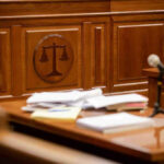 Wooden courtroom desk with papers and a microphone.