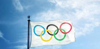 Olympic flag waving against a clear blue sky