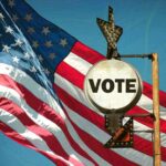 A vintage 'Vote' sign in front of an American flag