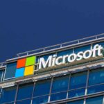 Gates Halts $77B in Funding to WOKE Causes! Microsoft logo on a modern corporate building against a blue sky