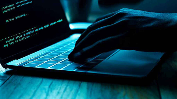 Hand typing on laptop with code on screen.