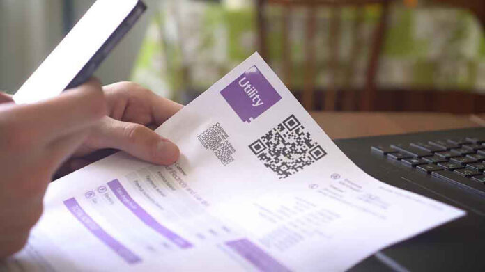 Hand holding utility bill with QR code