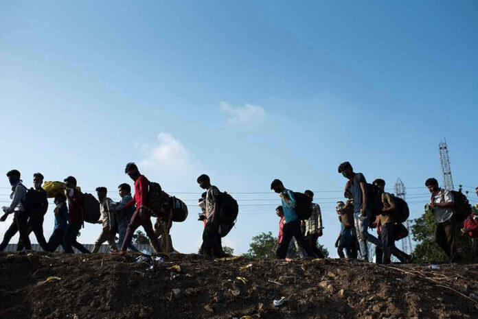 Line of people walking with backpacks outdoors.