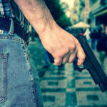 Violence Blame Game: Media Accused of BIAS Person holding a gun in a crowded street.