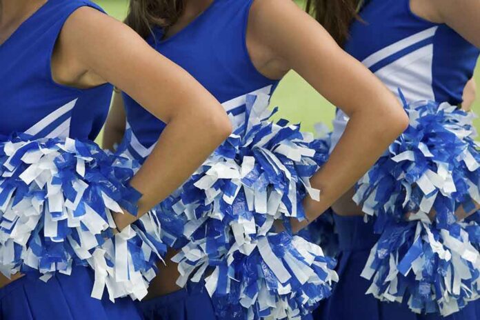 shutterstock_109441577.jpg Cheerleaders in blue and white uniforms holding pom poms
