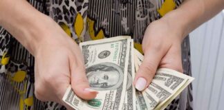 Hands holding a fan of hundred dollar bills
