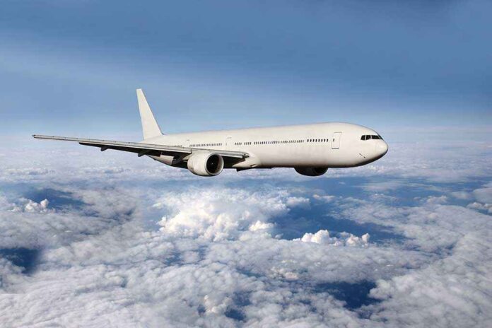 shutterstock_182272232.jpg A white airplane flying above fluffy clouds in a blue sky