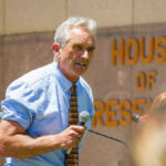 Man speaking into microphone outside House of Representatives