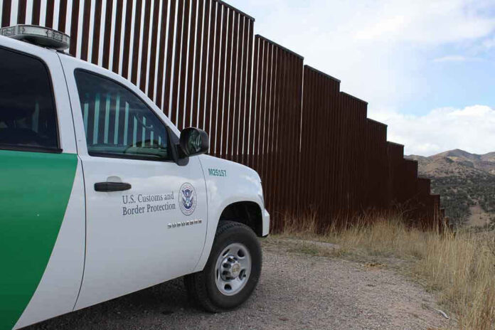 Border protection vehicle near a large metal fence