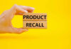Hand holding Product Recall blocks on yellow background
