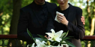 Mourners in black holding white flowers at funera