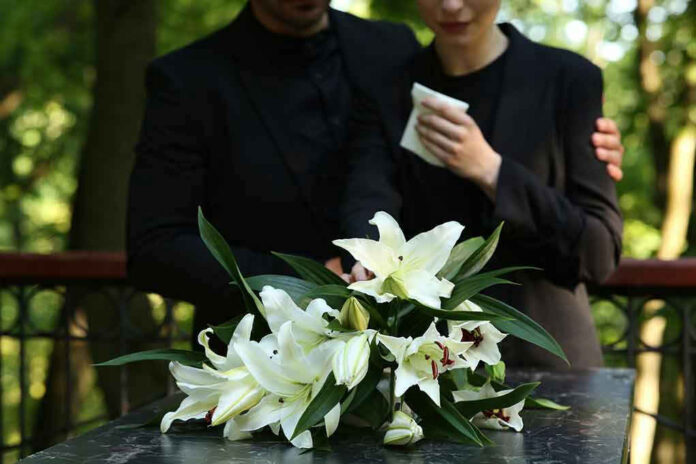 Mourners in black holding white flowers at funera