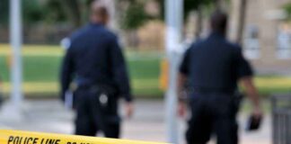 Police officers walking past caution tape at a crime scene