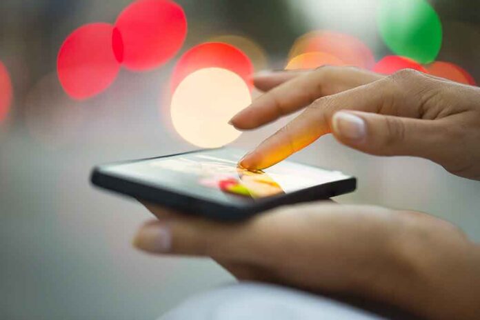 A person using a smartphone with a colorful bokeh background