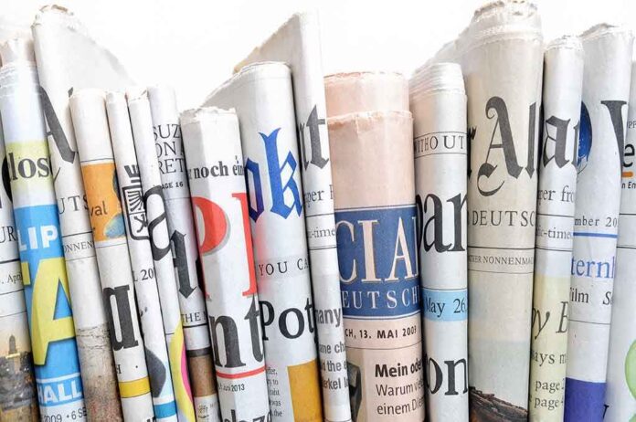 shutterstock_179149739.jpg A collection of rolled newspapers displaying various headlines and designs