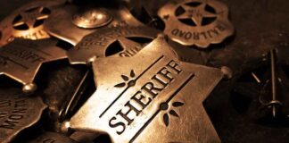 A collection of vintage sheriff badges arranged on a dark surface
