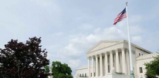 The US Supreme Court building with an American flag and landscaped grounds