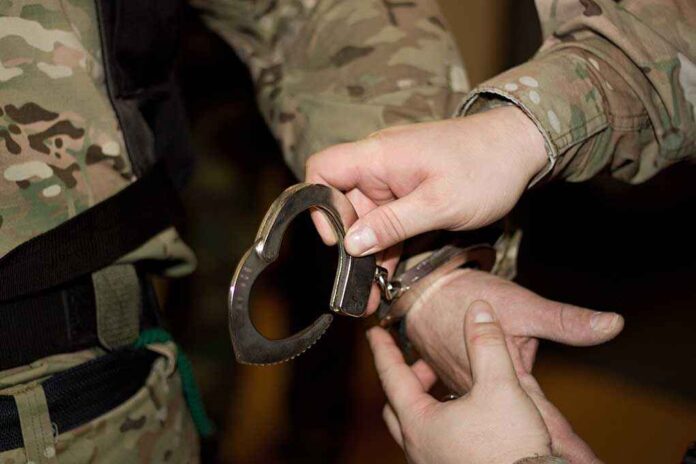 A military personnel placing handcuffs on an individual