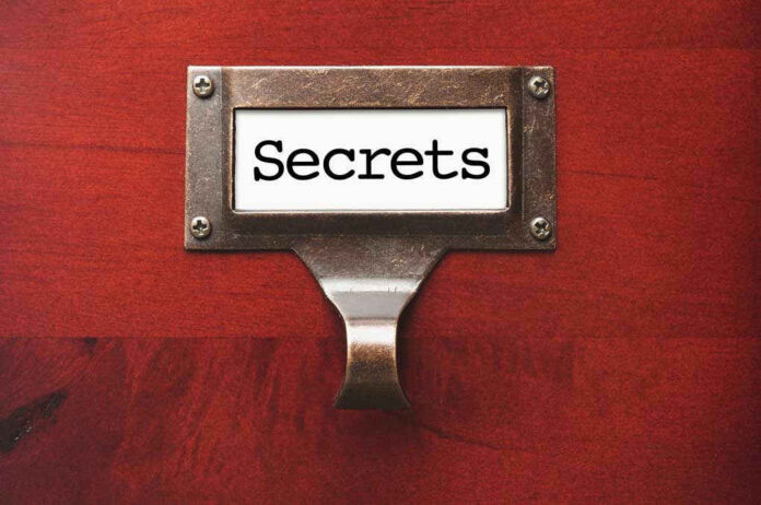 Metal label holder saying Secrets on wood background