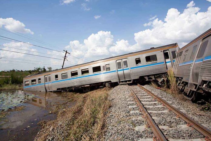 An overturned train on a railway track surrounded by vegetation