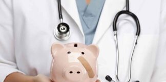 A doctor in a white coat holding a piggy bank with a bandage on it