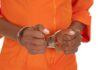 Hands of a person in handcuffs wearing an orange jumpsuit