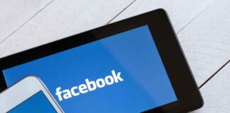 Smartphone and tablet displaying the Facebook logo on a wooden surface