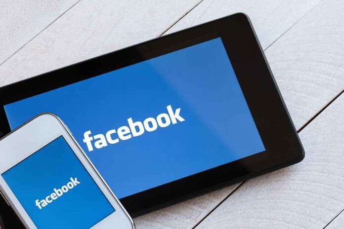 Smartphone and tablet displaying the Facebook logo on a wooden surface