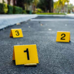 Crime scene markers on asphalt with bullet casing.