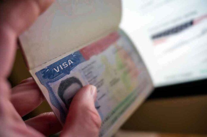 A hand holding an open passport displaying a visa page