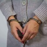 A person wearing handcuffs with their hands clasped together