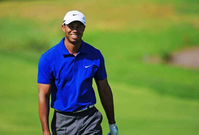 A smiling golfer wearing a blue shirt and white cap on a green golf course